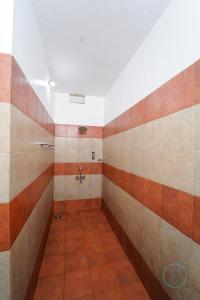 苏丹巴特利Le Eden Resort的浴室的墙壁上铺有橙色和棕色瓷砖。