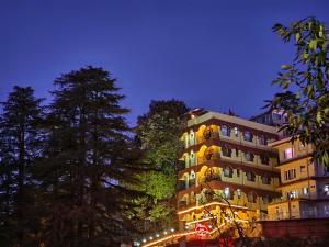 西姆拉Hotel Taj Palace near Mall Road的一座高大的建筑,晚上有灯