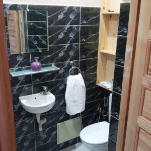 马拉喀什Villa Paradis的黑色瓷砖浴室设有卫生间和水槽