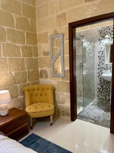 KerċemDaner Ta’ Pantu House的浴室设有黄色椅子和玻璃淋浴间
