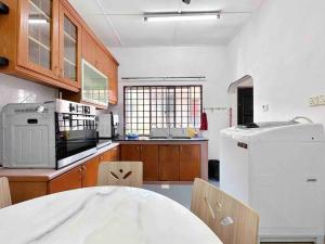士姑来TAMAN UNIVERSITI THREE BEDROOMS 6-10Pax UTM, SKUDAI的厨房配有桌子和白色冰箱。