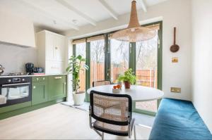 伦敦Spring Stays Cosy 2-Bed Residence with Free Parking的厨房配有绿色橱柜和白色桌椅