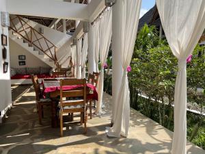 瓦塔穆Paka House-Rafiki Village的庭院配有桌椅和白色窗帘