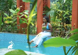 Kizhake ChālakudiBack to Roots Ayurveda Retreat的坐在游泳池边缘的女人