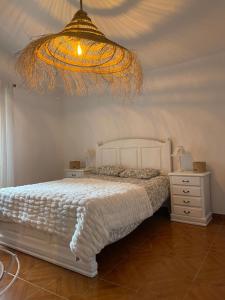 Farelos de BaixoParaíso dos Avós的卧室配有白色的床和吊灯。