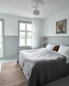 锡尔克堡Hotel Ny Hattenæs的白色卧室设有一张大床和两个窗户