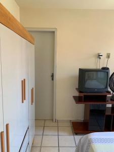 瓜拉派瑞APTO PRAIA DO MORRO, 02 QUARTOS C SUITE, WI-FI, GARAGEM, 1 ANDAR ESCADA.的一间房间,在隔壁的桌子上配有电视