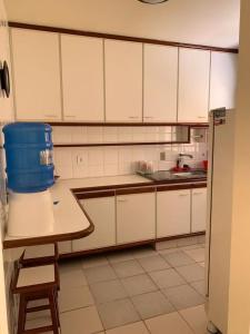 瓜拉派瑞APTO PRAIA DO MORRO, 02 QUARTOS C SUITE, WI-FI, GARAGEM, 1 ANDAR ESCADA.的厨房配有白色橱柜和一张桌子上的蓝色桶