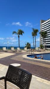 萨尔瓦多Apartamento beira mar localizado no Ondina Apart Hotel的棕榈树游泳池旁的长凳