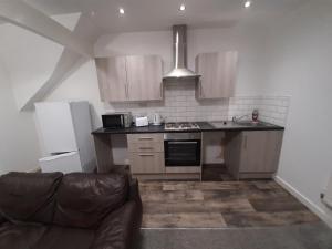 米德尔斯伯勒Exclusive Self-contained flat in Middlesbrough的一个带木制橱柜的厨房和一个沙发