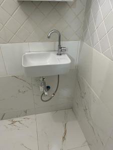大坎普Quarto privativo em casa domiciliar的白色瓷砖浴室内的白色水槽
