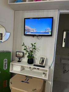 大坎普Quarto privativo em casa domiciliar的墙上的电视,带笔记本电脑的书桌