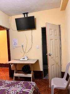 危地马拉Hotel Canaan La aurora的客房设有书桌和墙上的电视。
