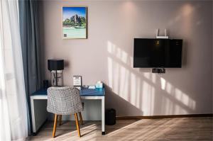 海盐嘉兴海盐科技城兰欧酒店的一张桌子,电视机和椅子放在房间里