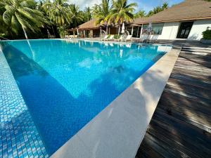 曼度Fiyavalhu Resort Maldives的一座铺有蓝色瓷砖地板的游泳池和一座房子