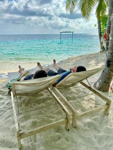 曼度Fiyavalhu Resort Maldives的一群人躺在海滩上的吊床上