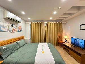 胡志明市NEW LAND Apartment 2 - Phu My Hung的一间卧室配有一张床、一张书桌和一台电视