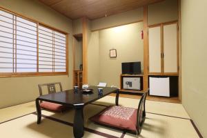 草津高松酒店的客厅配有桌子和电视