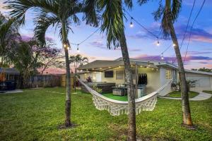 彭布罗克派恩斯7-Person Luxury Spa, Fenced Paradise, Beach Vibes的棕榈树庭院内带吊床的房子