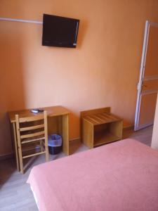 佩皮尼昂贝瑞酒店的一间卧室配有一张桌子和一台墙上的电视。