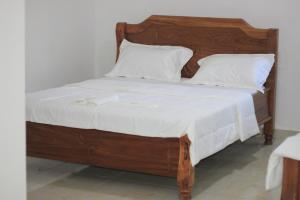 丰博尼Faradel Motel的一间卧室配有一张带白色床单的木床