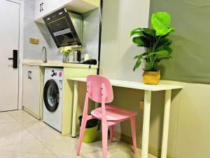 上海自在居公寓酒店(上海川沙古镇店)的厨房里一张桌子下面的粉红色椅子