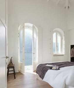 波尼亚纳拉廖科莫湖拉里奥公寓式酒店的白色卧室设有床和开放式窗户