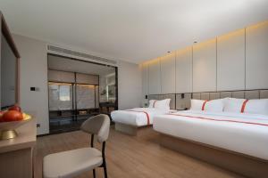 腾冲格林东方酒店(腾冲东湖公园店)的酒店客房,配有两张床和椅子
