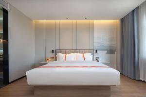 腾冲格林东方酒店(腾冲东湖公园店)的卧室配有白色大床和白色枕头