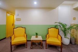 新德里Bloom Hotel - Karol Bagh的两个黄色的椅子和一张桌子