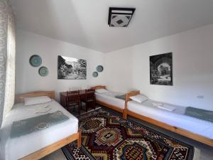 布哈拉Rumi Hotel & Hostel的一间设有两张床和一张桌子及椅子的房间