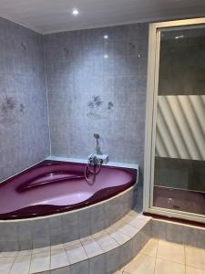 EpfigMaison-Le Cocon De Marguerite的带窗户的浴室内的紫色浴缸