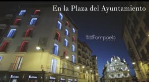 潘普洛纳Hotel Pompaelo Plaza del Ayuntamiento & Spa的夜幕降临的城市街道上一座高楼