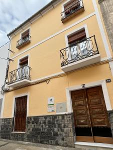 蒙蒂利亚Casa Cordón的黄色的建筑,设有两个阳台和两个门