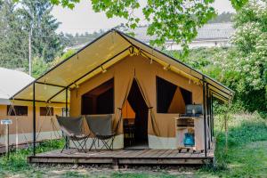 孔东Camping Onlycamp L'Argenté的木制甲板上带椅子的黄色帐篷