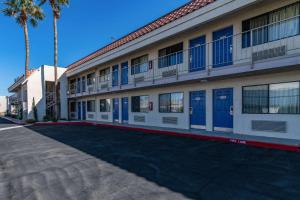 Thousand PalmsRodeway Inn & Suites Thousand Palms - Rancho Mirage的街上有蓝色门和棕榈树的建筑