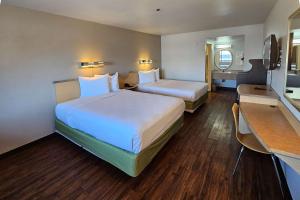 Thousand PalmsRodeway Inn & Suites Thousand Palms - Rancho Mirage的酒店客房配有两张床和一张书桌