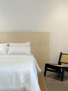 古晋Heritage Vacation Inn Balcony的卧室配有白色的床和椅子