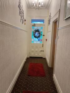 波斯考尔Villa Guest House的走廊上设有一扇门,上面有红色地毯和窗户