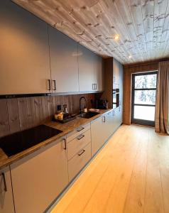 NoresundNorebu - Norefjell的厨房铺有木地板,配有白色橱柜。