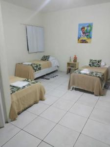 德尔米鲁戈韦亚Bom Sossego Pousada DG的客房设有两张床,铺有白色瓷砖地板。