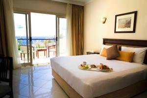 沙姆沙伊赫大绿洲度假酒店的一间酒店客房,配有一张床铺,上面放着一个食物托盘