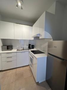 布鲁塞尔Appartement lumineux dans un quartier animé的厨房配有白色橱柜和冰箱。
