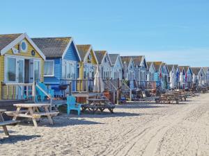 IfordEl Nido - Self Catering cabin in Southbourne, 5 mins from beach的海滩上一排房子,有长椅和桌子