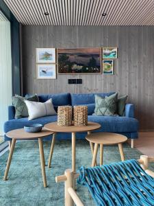 亨宁斯韦尔Waterfront apartment with panoramic sea view的客厅配有蓝色的沙发和2张桌子