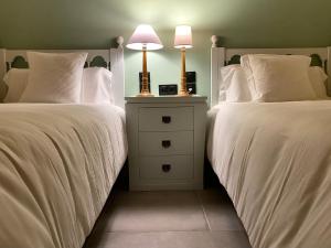 莱萨卡Fondamaria - Alojamiento rural的两张带白色床单的床和床头柜上的一盏灯