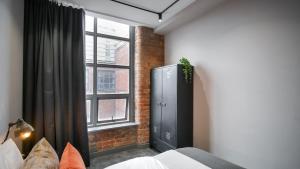 曼彻斯特Manhattan by The Heim Residences的卧室在窗户前设有黑色橱柜