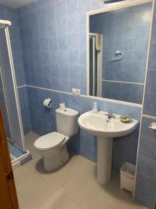 鲁伊德拉Hostal y Apartamentos la Vereda的蓝色瓷砖浴室设有卫生间和水槽