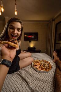 卡博迪圣阿戈斯蒂尼奥Reserva do Paiva suites的坐在床上吃一块比萨饼的女人