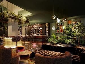 苏黎世The Home Hotel Zürich - a member of DESIGN HOTELS的一间酒吧,配有沙发、椅子和植物